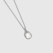 Silver necklace with a round pendant on a light gray background