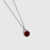 Silver necklace with a red gemstone pendant on a white background