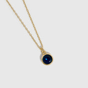 Gold necklace with a red gemstone pendant on a white background