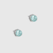 Two turquoise gemstones on a light gray background
