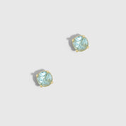 Pair of earrings with light blue gemstones on a light gray background
