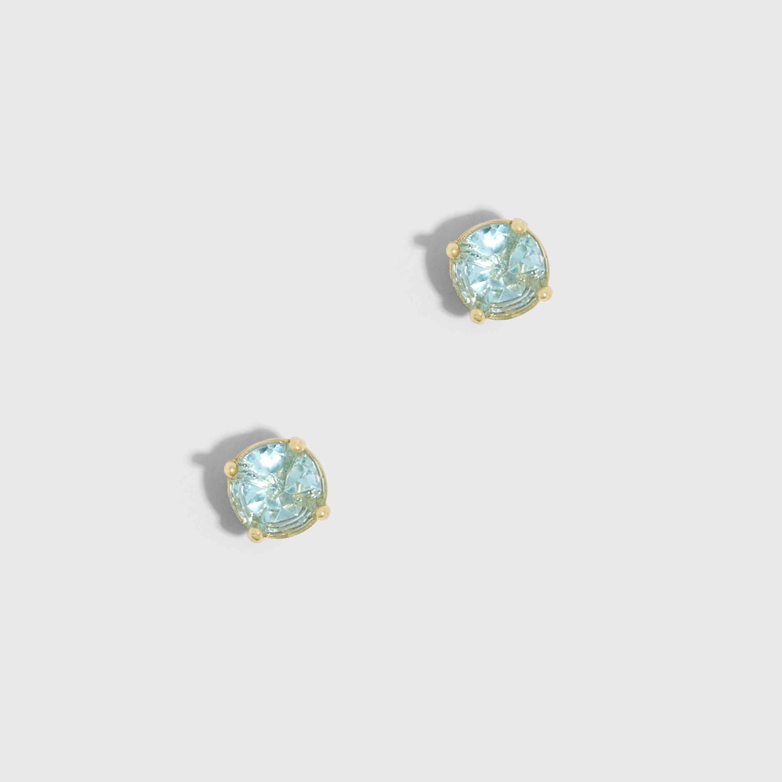Pair of earrings with light blue gemstones on a light gray background
