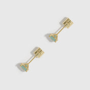 Gold earrings with triangular gemstones on a light gray background