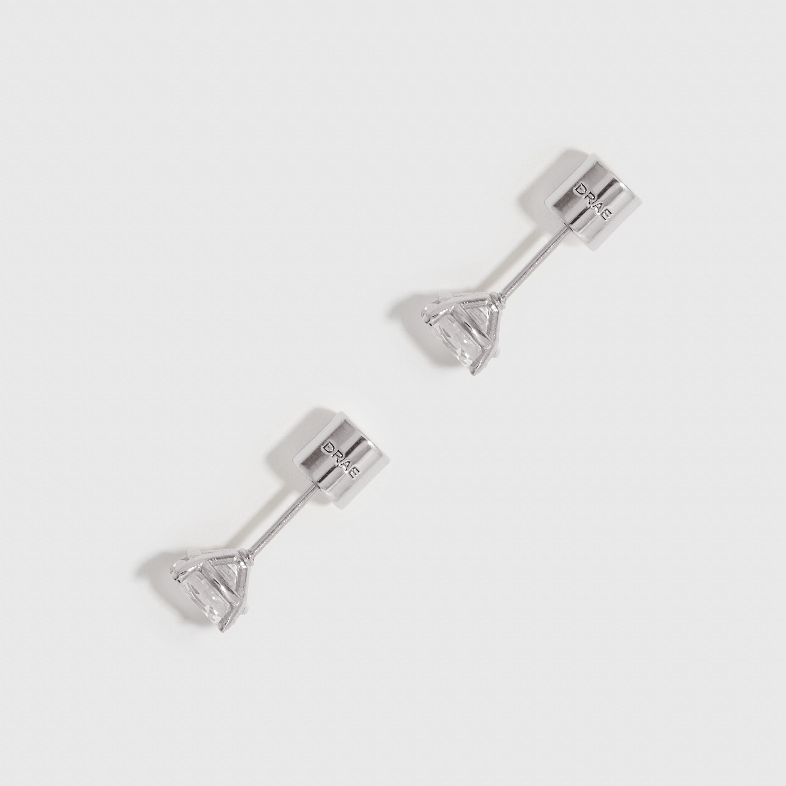 Pair of silver stud earrings on a light gray background