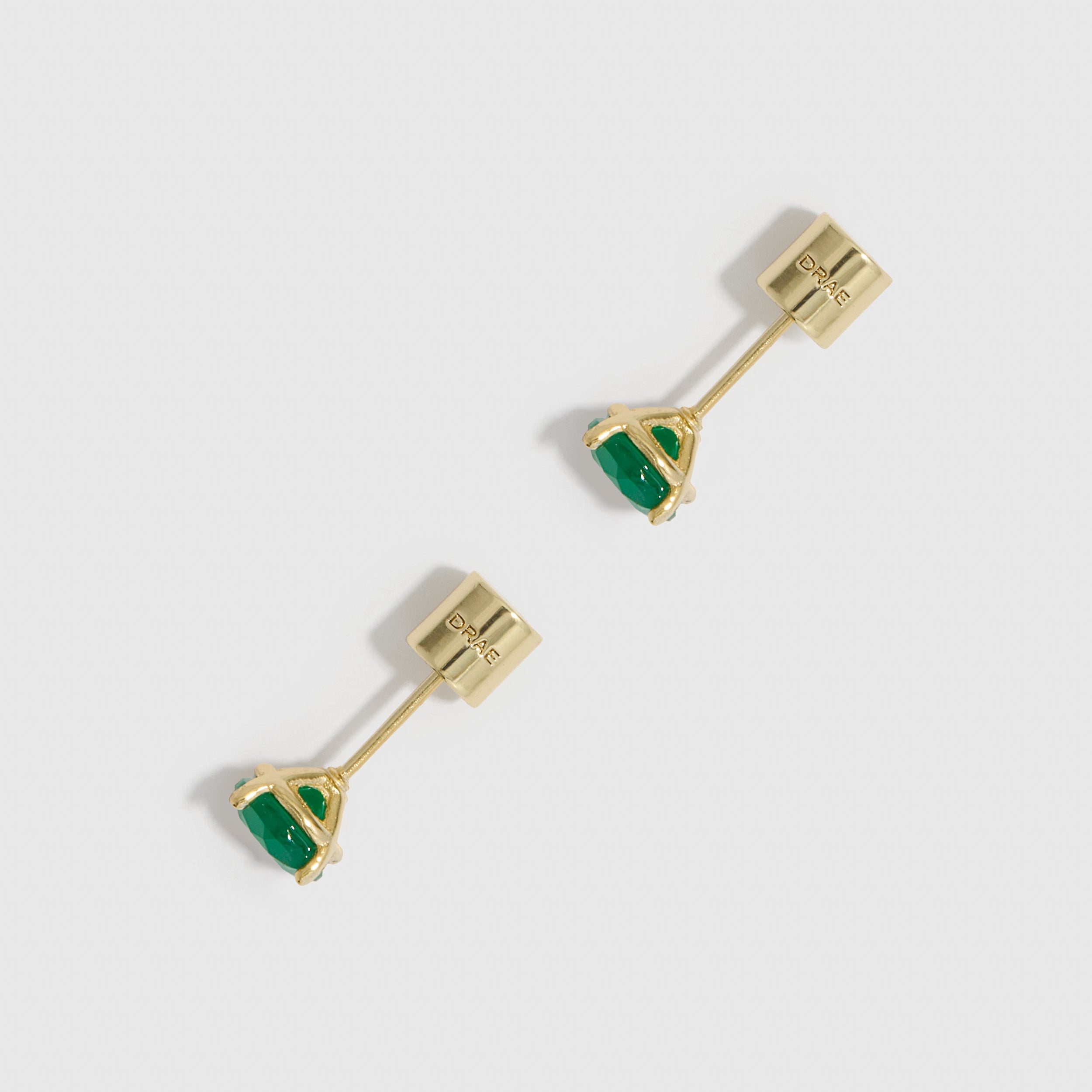 Gold earrings with green gemstones on a white background