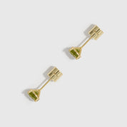 Gold earrings with green gemstones on a white background