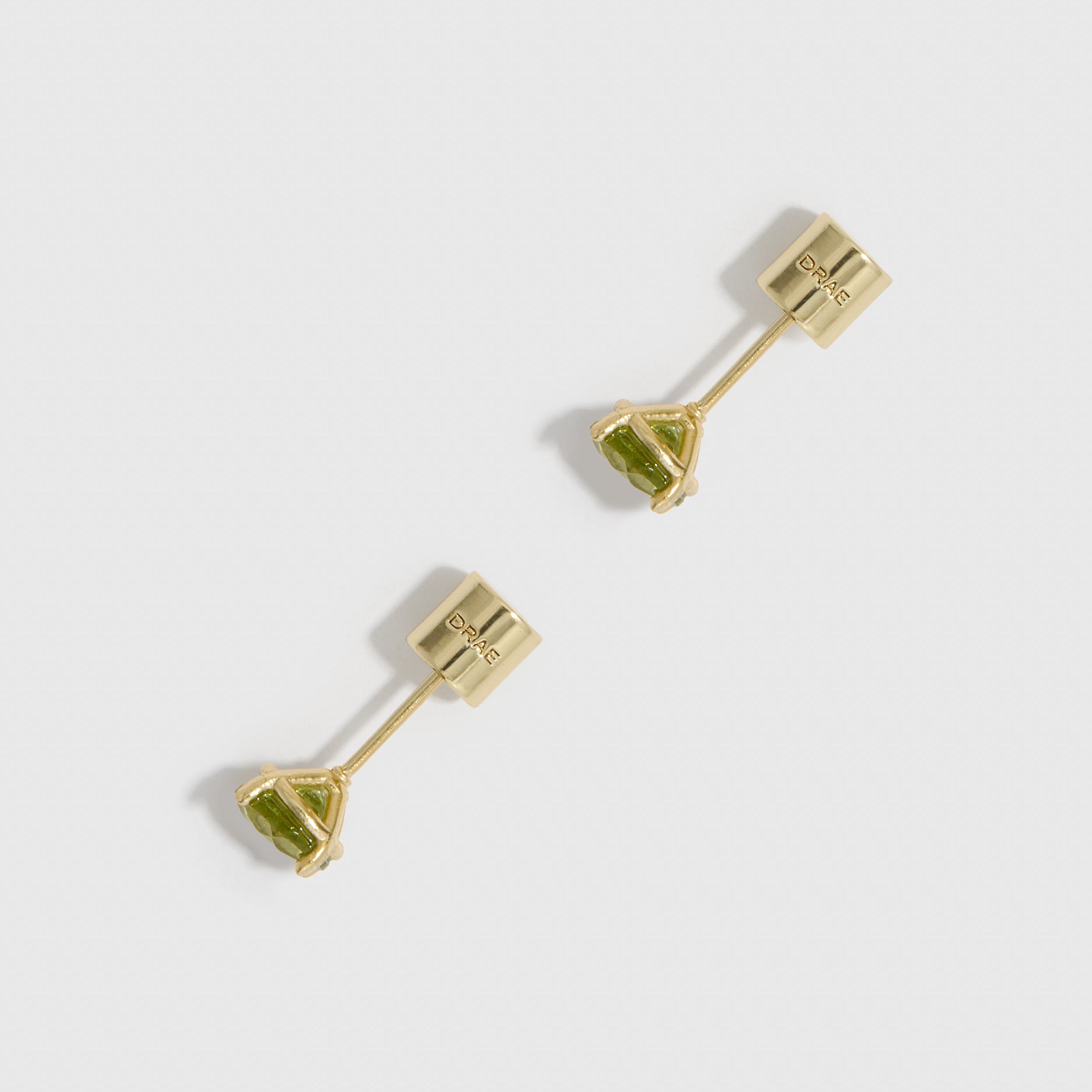 Gold earrings with green gemstones on a white background