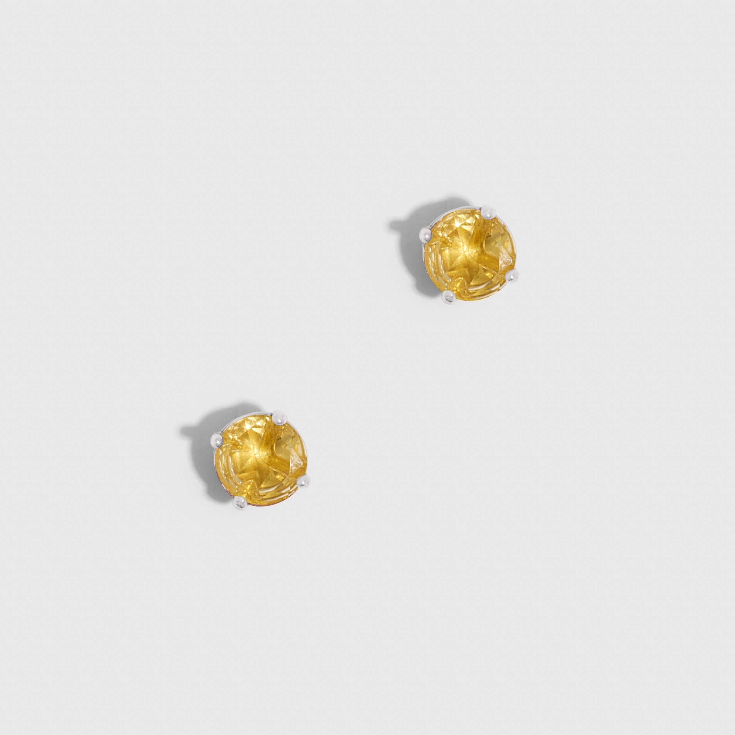 Pair of gold lion head earrings on a light gray background