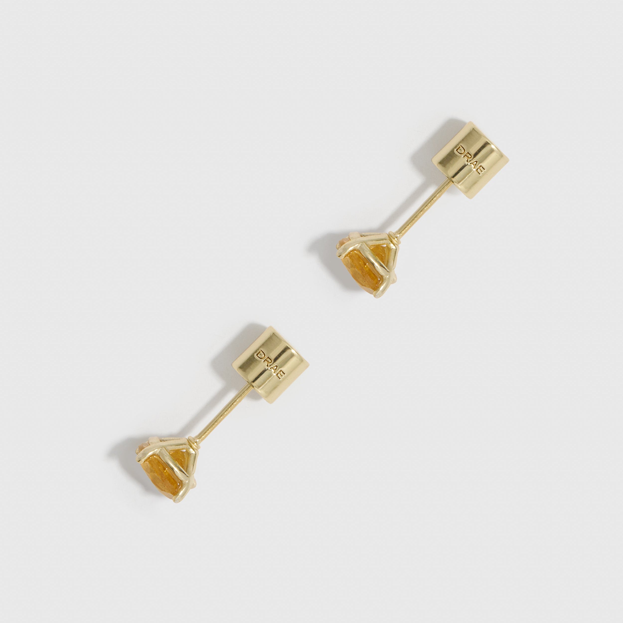 Gold earrings on a light gray background