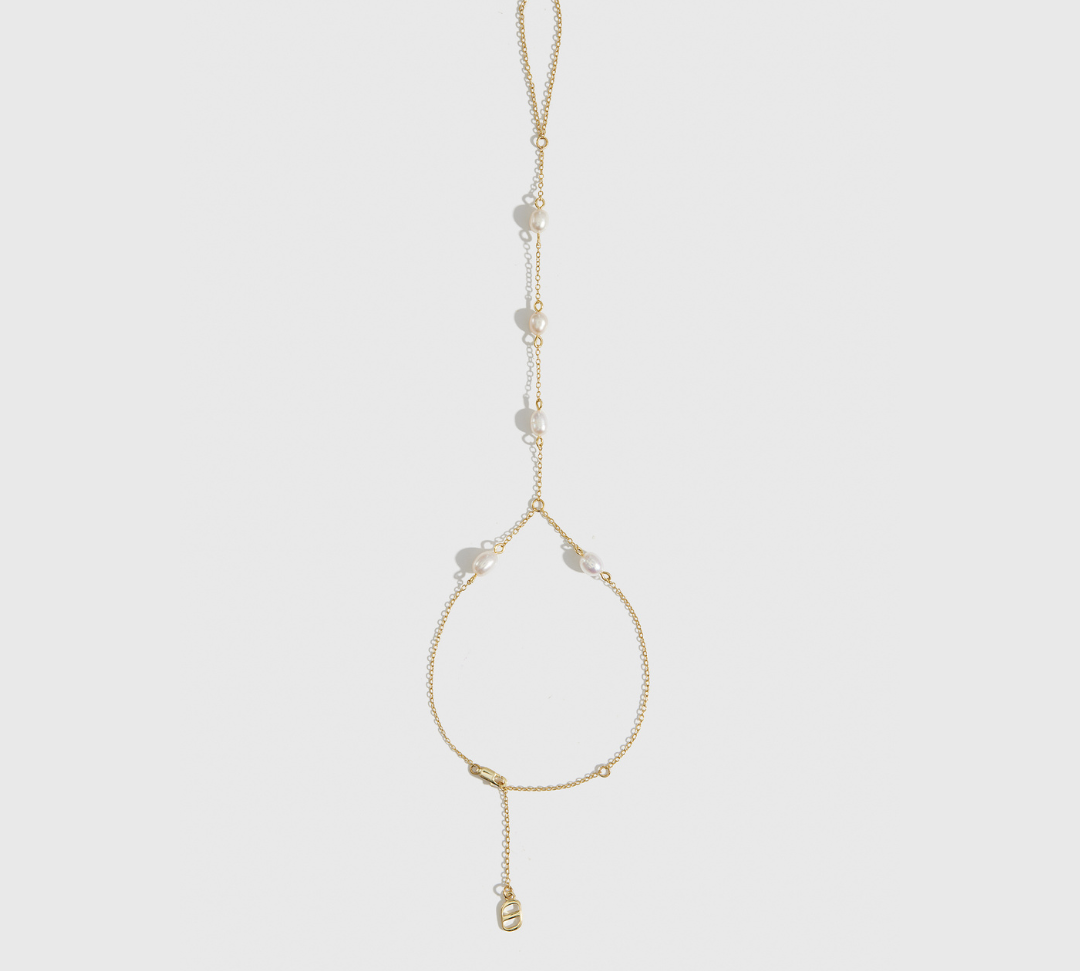 14k gold plated sterling silver 925 dainty freshwater pearl hand chain with freshwater pearls, shown on a plain background.