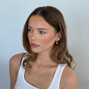 Woman wearing a white tank top against a plain background