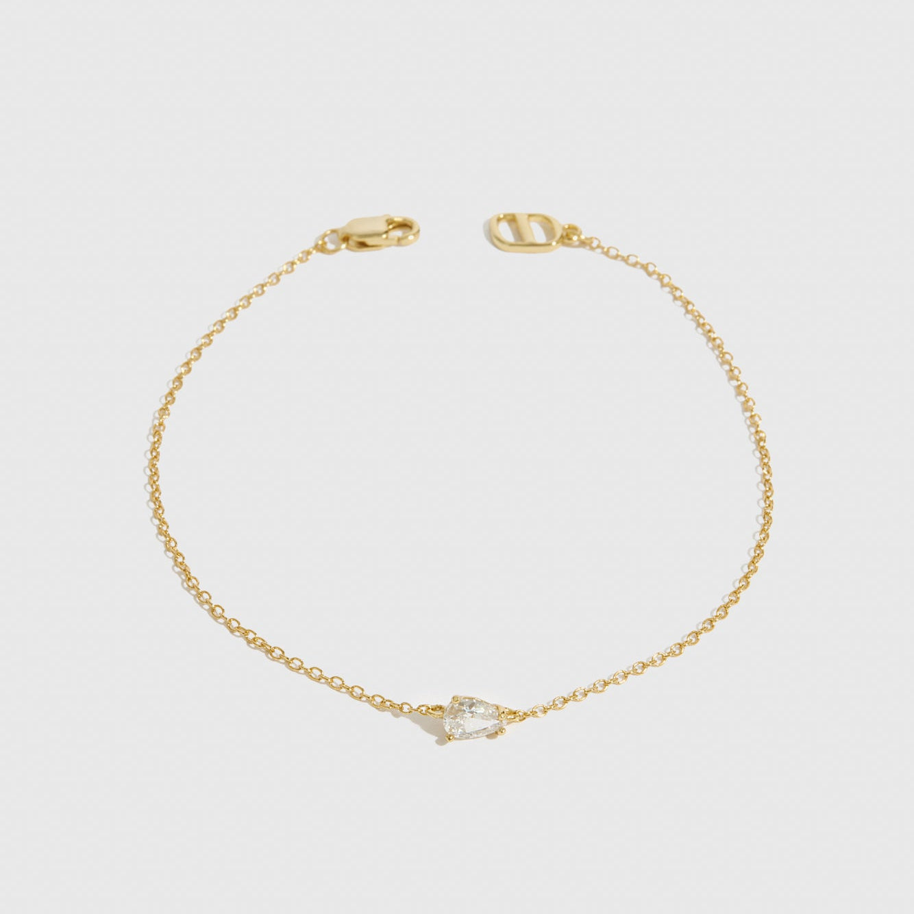 14k gold plated sterling silver 925 mini teardrop-cut solitaire bracelet with a pure white cubic zirconia, shown on a plain background.
