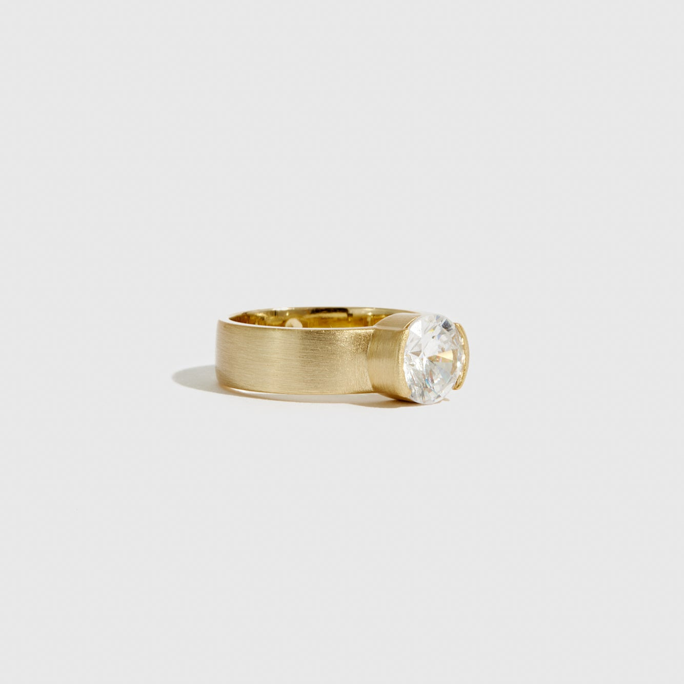 Gold ring with a clear gemstone on a light gray background