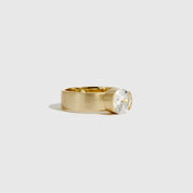 Gold ring with a clear gemstone on a light gray background