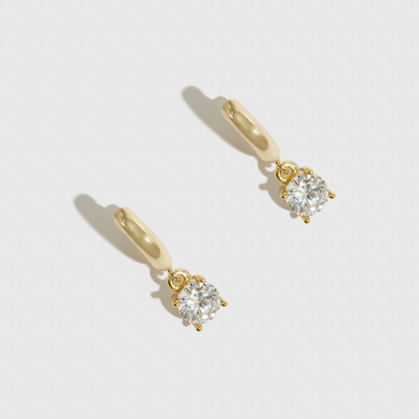 14k gold plated sterling silver 925 round-cut solitaire huggies with a pure white cubic zirconia, shown on a plain background.