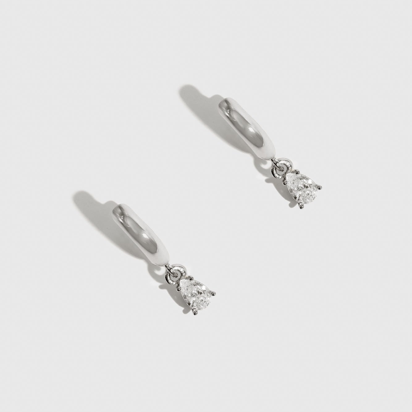 Sterling silver 925 mini teardrop-cut solitaire huggies with a pure white cubic zirconia, shown on a plain background.