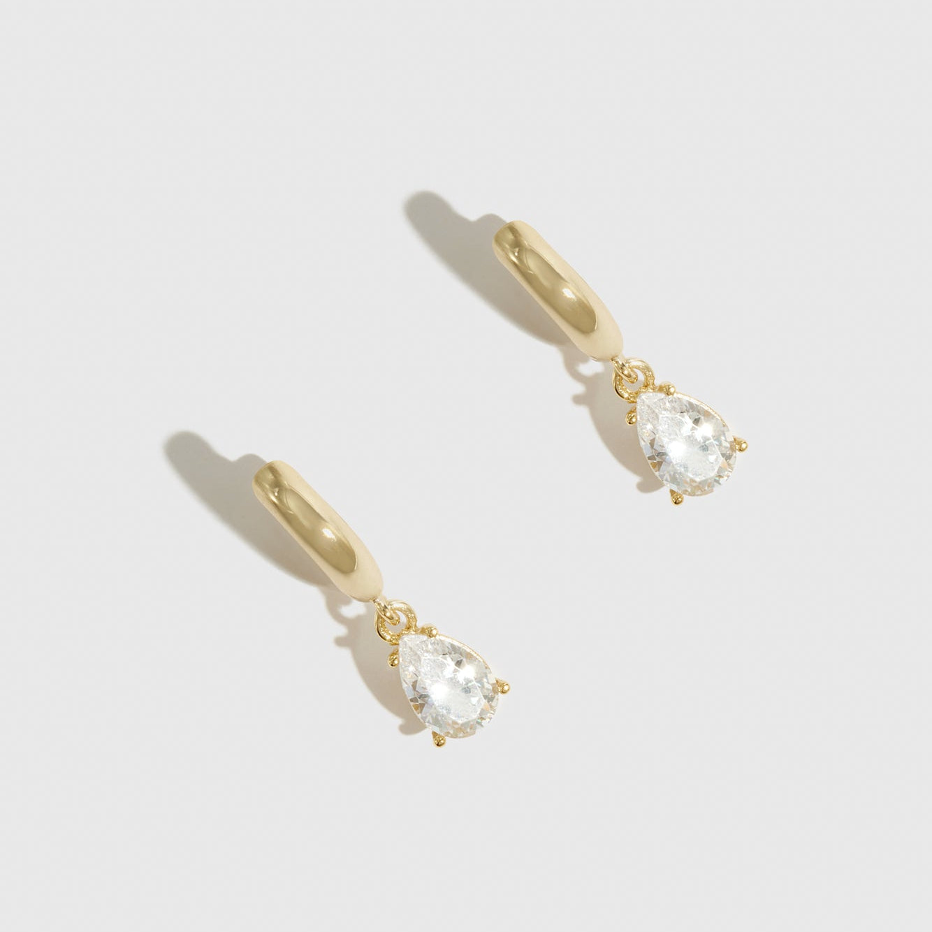 14k gold plated sterling silver 925 regular teardrop-cut solitaire huggies with a pure white cubic zirconia, shown on a plain background.