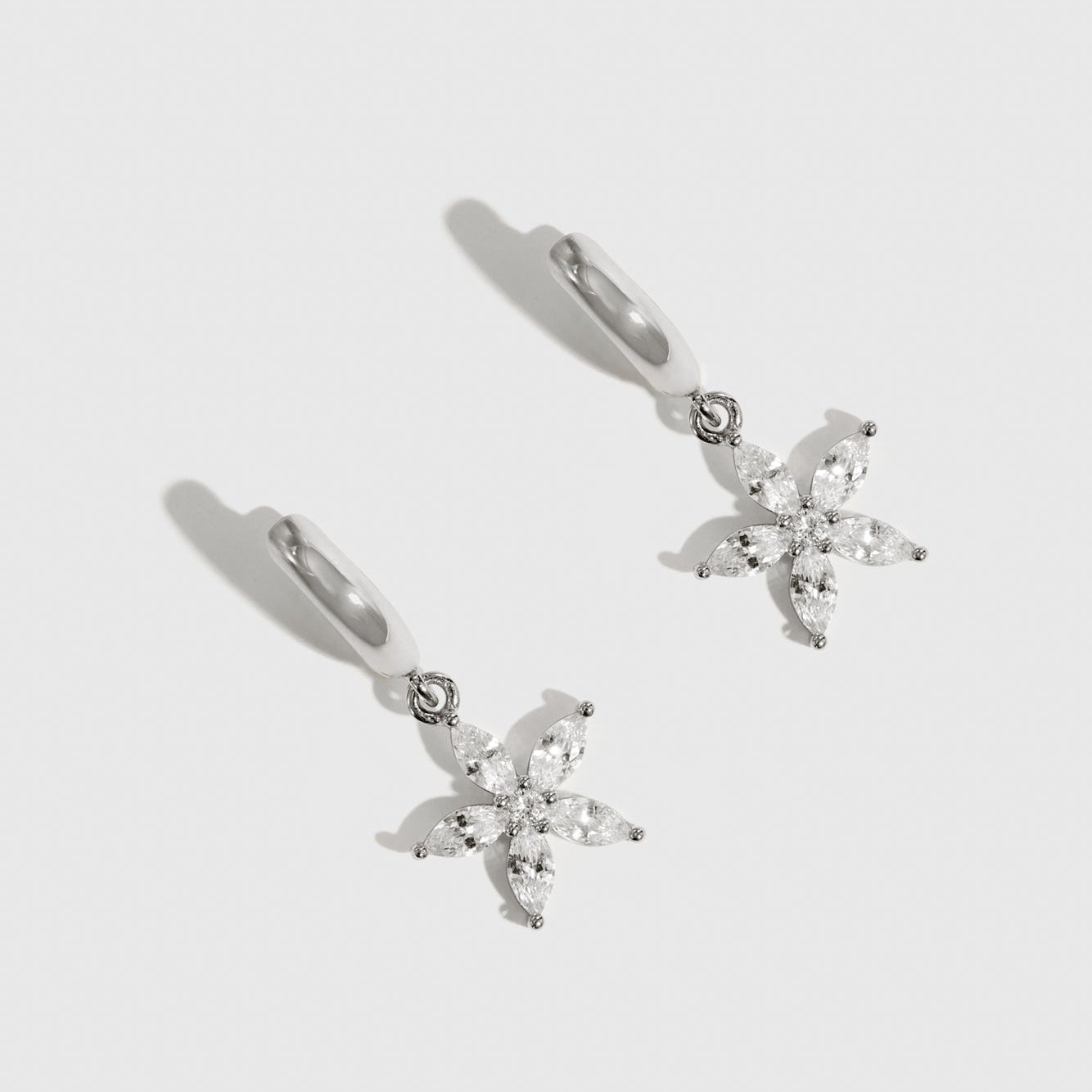 Sterling silver 925 flower solitaire huggies with a pure white cubic zirconia, shown on a plain background.