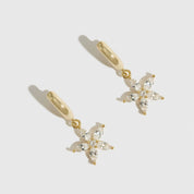 14k gold plated sterling silver 925 flower solitaire huggies with a pure white cubic zirconia, shown on a plain background.