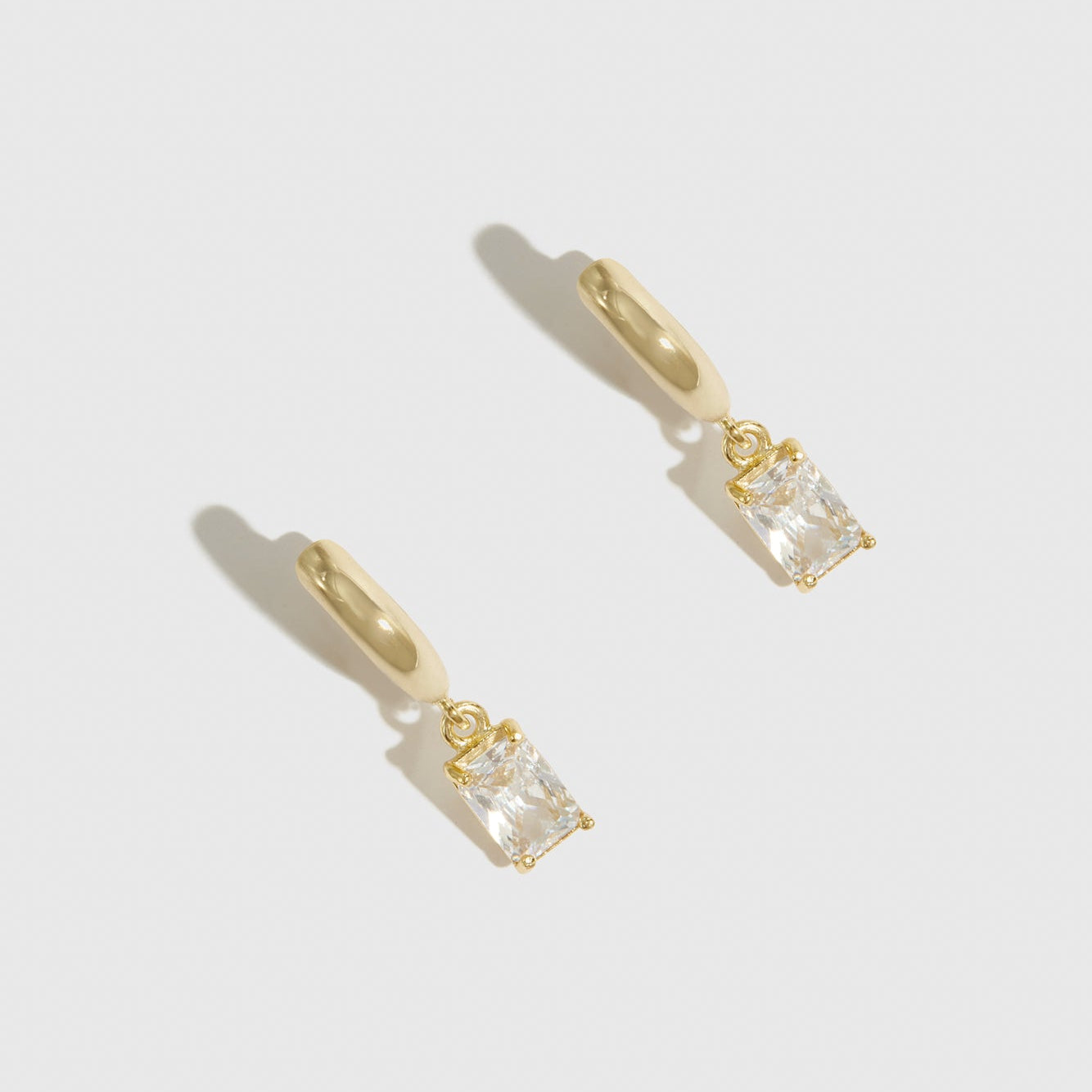 14k gold plated sterling silver 925 baguette-cut solitaire huggies with a pure white cubic zirconia, shown on a plain background.