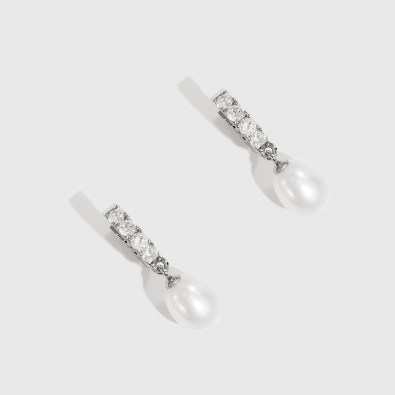 Sterling silver 925 freshwater pearl pavé huggies with cubic zirconia and a freshwater pearl, shown on a plain background.