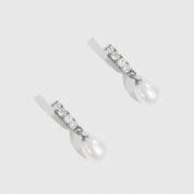 Sterling silver 925 freshwater pearl pavé huggies with cubic zirconia and a freshwater pearl, shown on a plain background.
