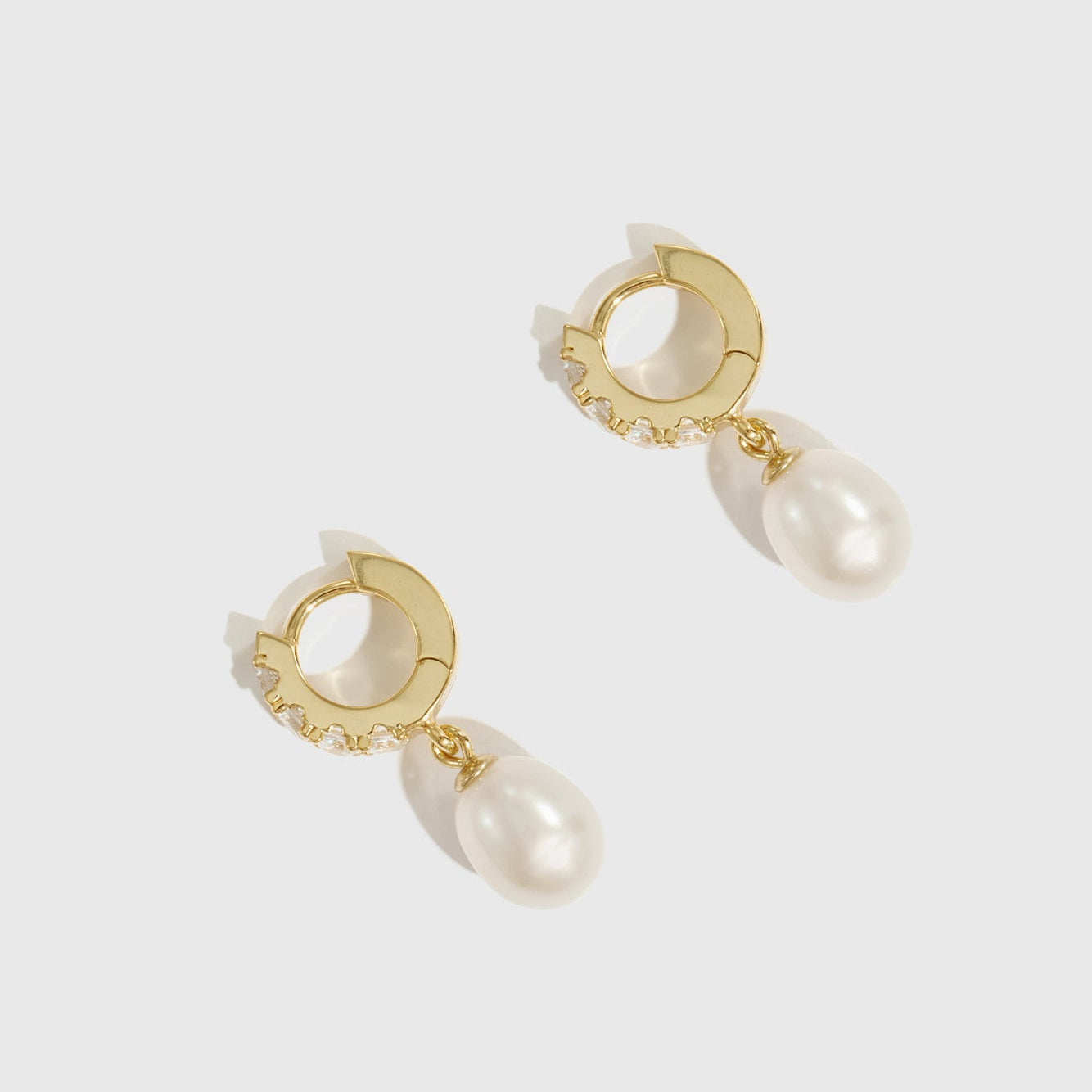 Gold hoop earrings with pearl drops on a white background