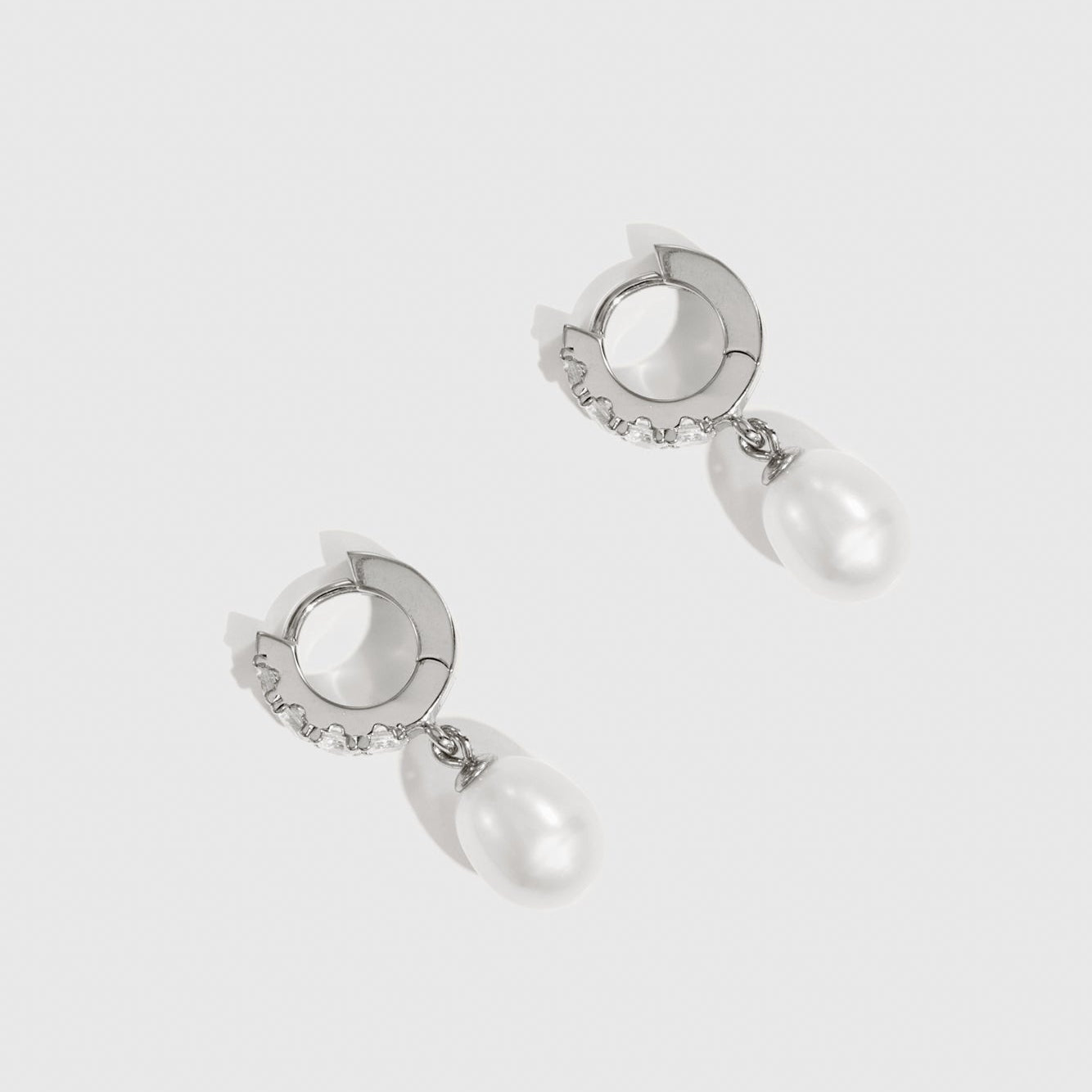 Pair of silver earrings with pearl drops on a white background