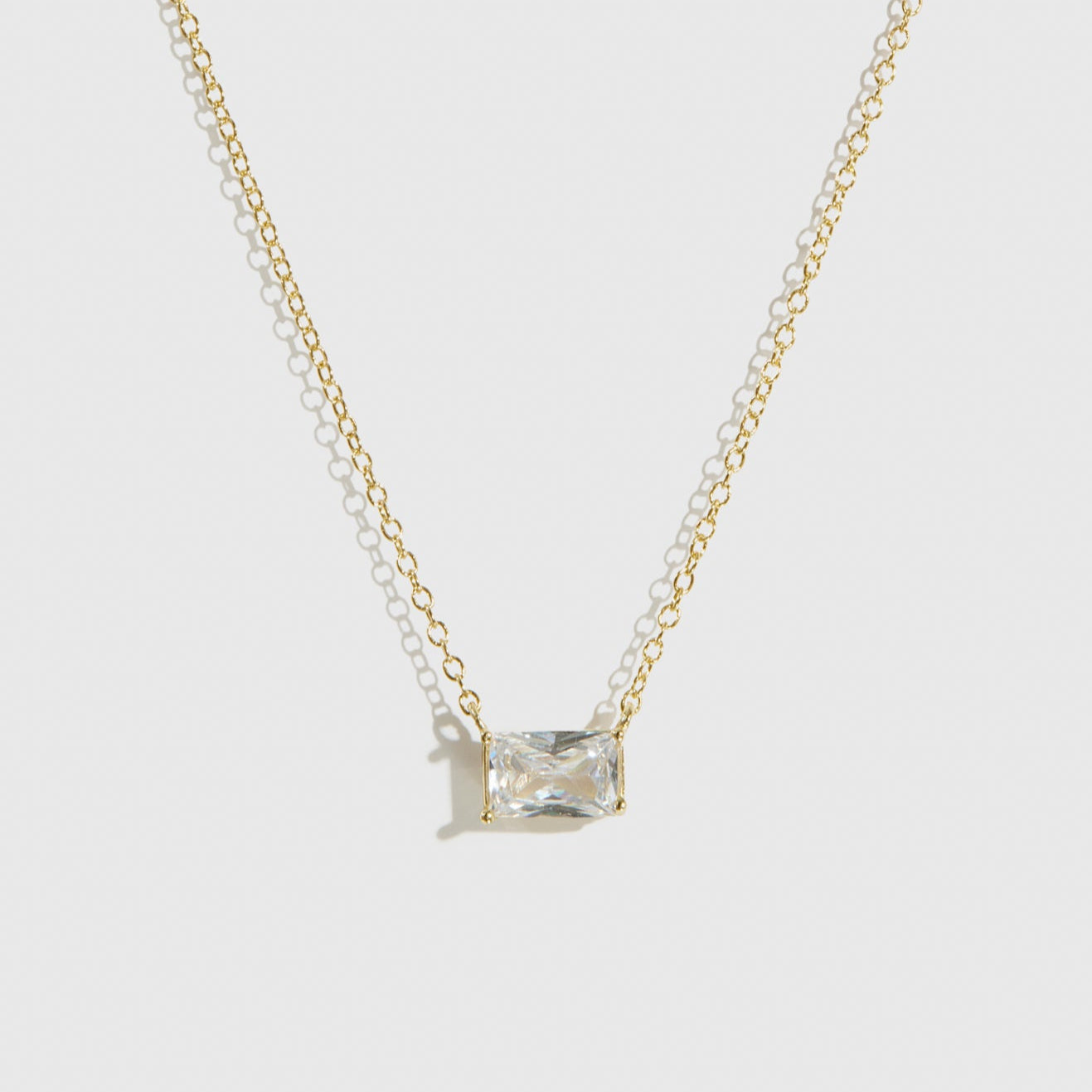 14k gold plated sterling silver 925 baguette-cut solitaire necklace with a pure white cubic zirconia, shown on a plain background.