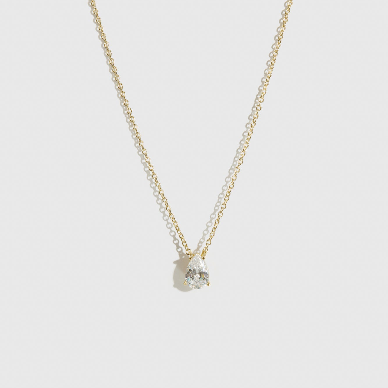 14k gold plated sterling silver 925 mini teardrop-cut solitaire necklace with a pure white cubic zirconia, shown on a plain background.