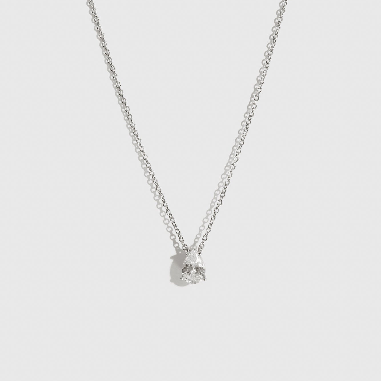 Sterling silver 925 mini teardrop-cut solitaire necklace with a pure white cubic zirconia, shown on a plain background.