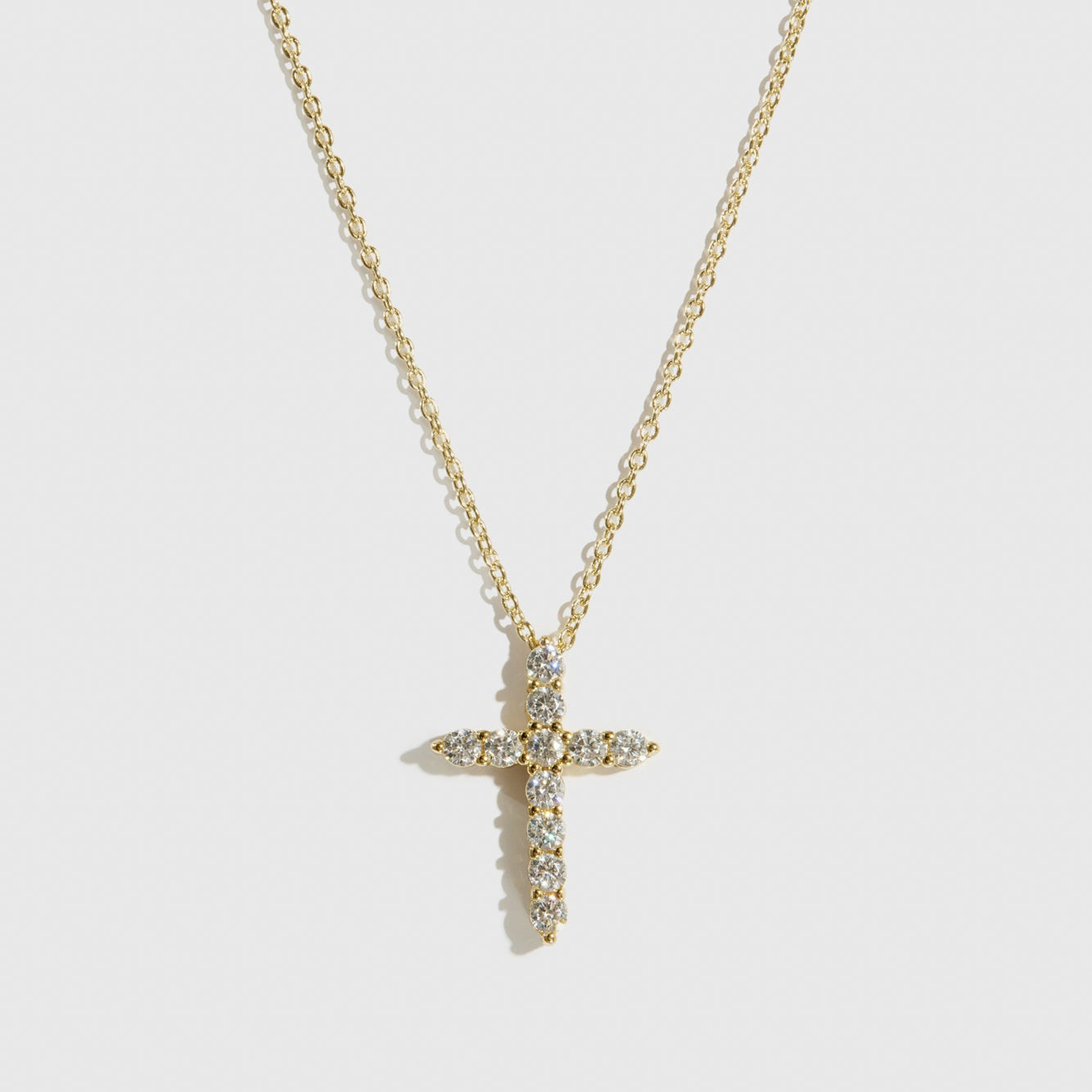 14k gold plated sterling silver 925 mini dainty pavé cross necklace with cubic zirconia, shown on a plain background.