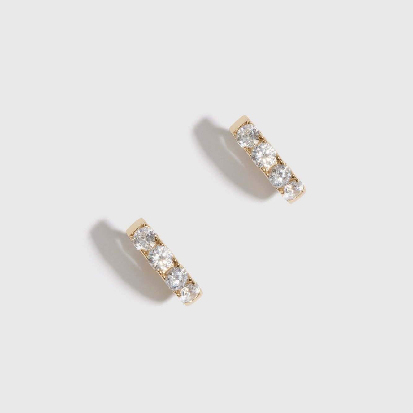 14k gold plated sterling silver 925 mini pavé huggie earrings with pavé cubic zirconia, shown on a plain background.