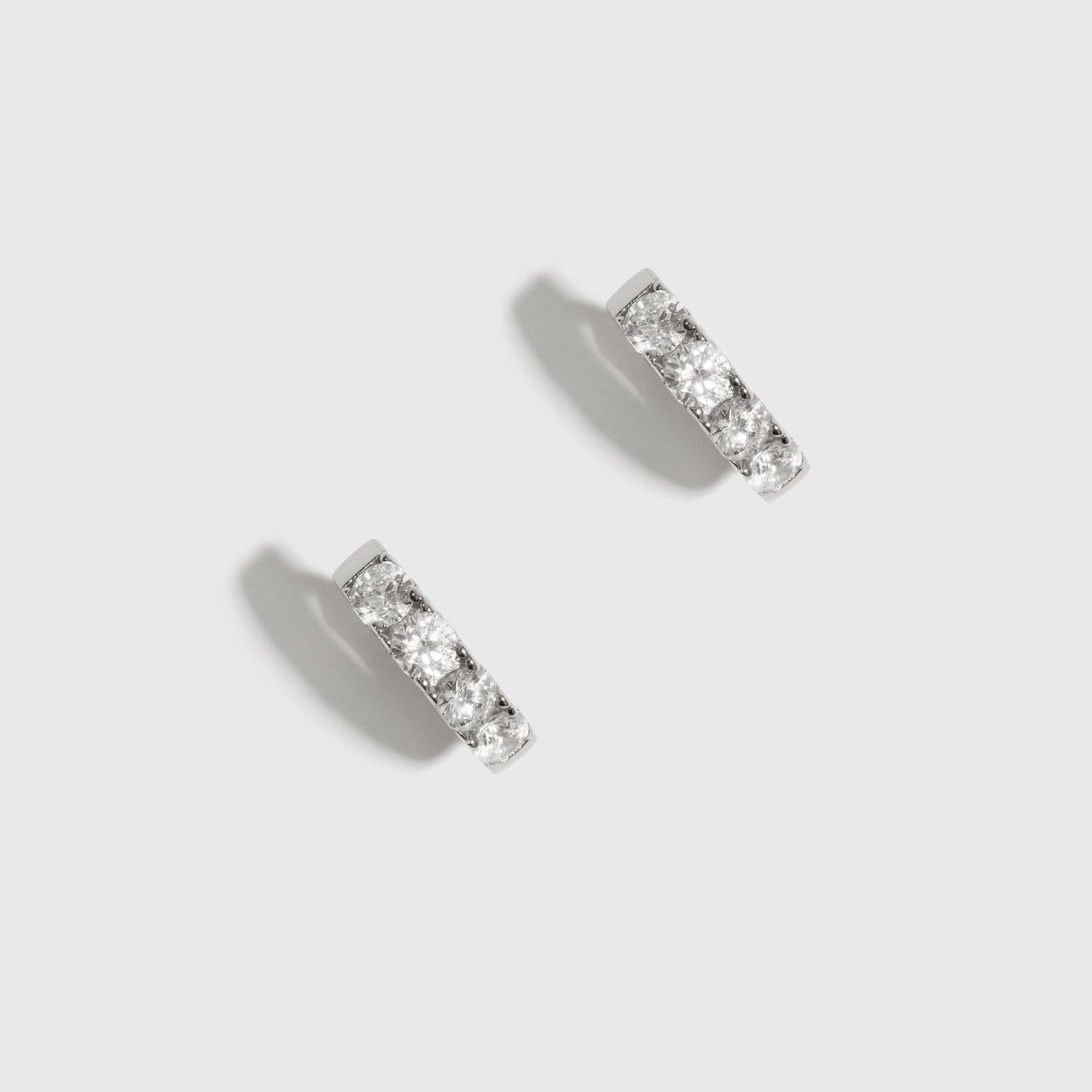 Sterling silver 925 mini pavé huggie earrings with pavé cubic zirconia, shown on a plain background.