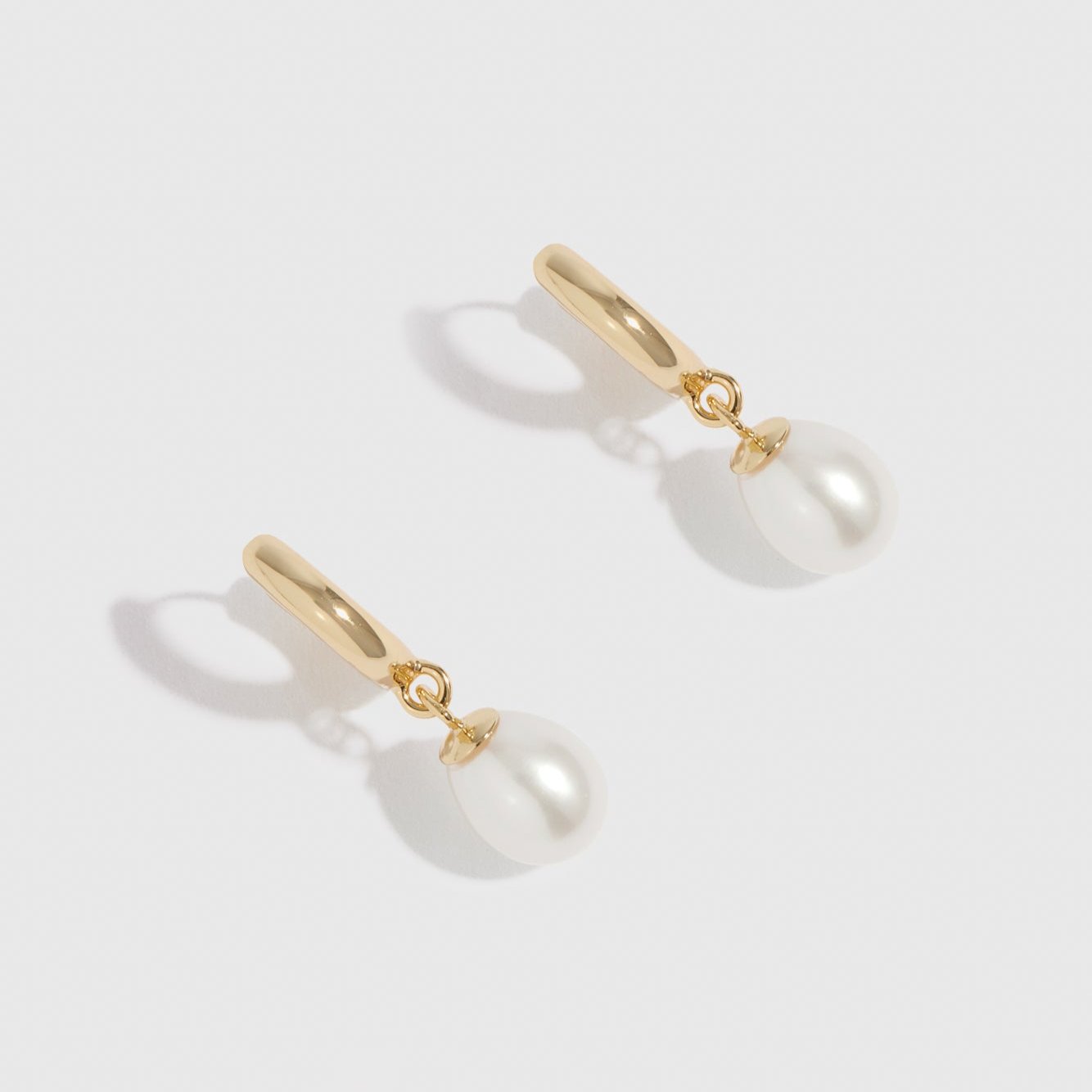 14k gold plated sterling silver 925 freshwater pearl huggie earrings with freshwater pearls, shown on a plain background.