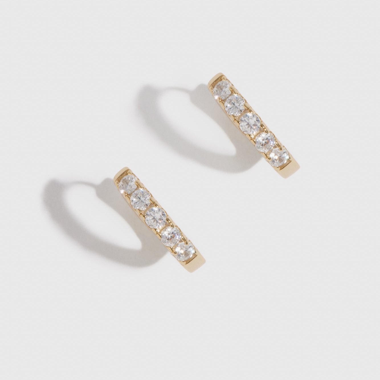 14k gold plated sterling silver 925 classic pavé huggie earrings with pavé cubic zirconia, shown on a plain background.