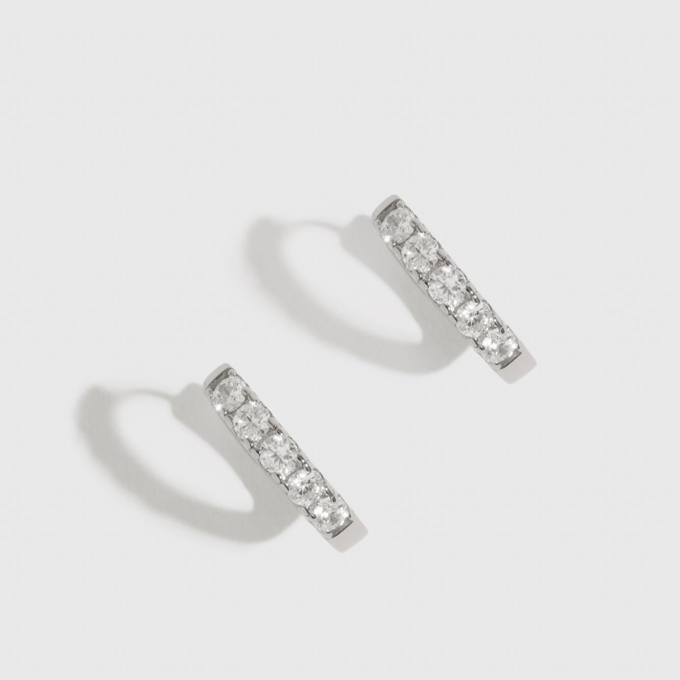 Sterling silver 925 classic pavé huggie earrings with pavé cubic zirconia, shown on a plain background.