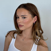 Woman wearing a white tank top against a plain background