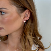 Close-up of a woman wearing earrings with a plain background