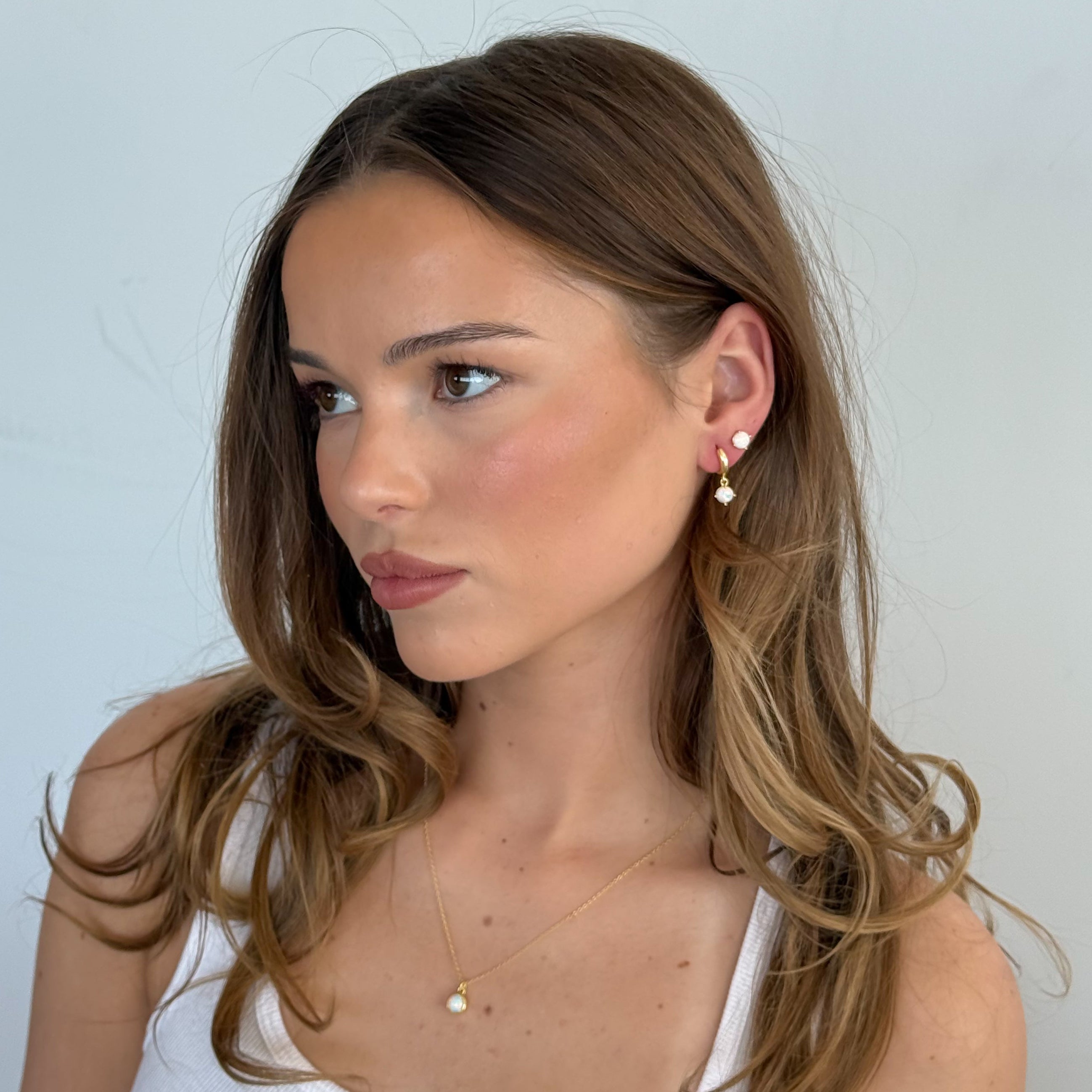 Woman wearing a white tank top against a light gray background