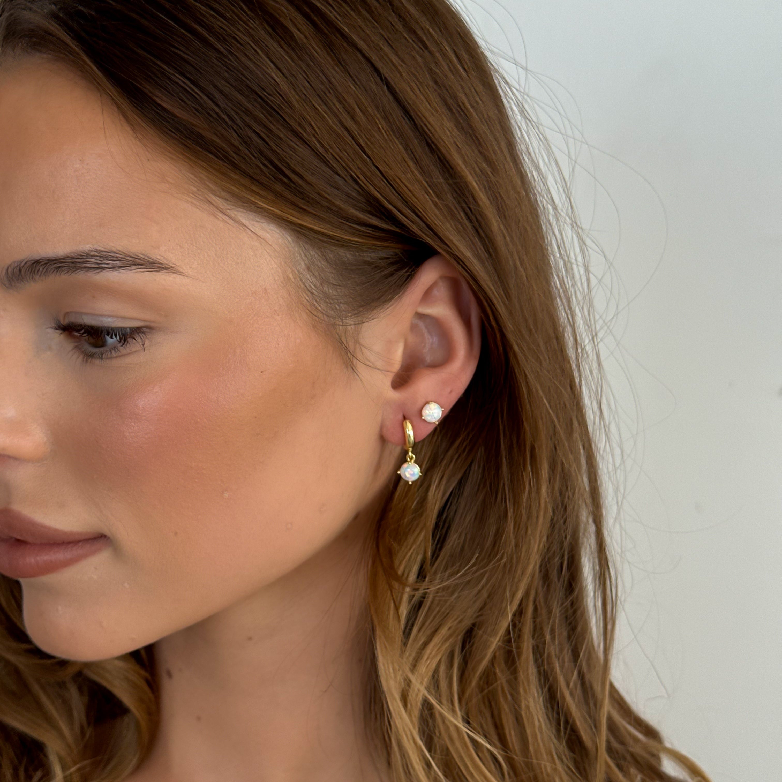Woman wearing gold hoop earrings with a plain background