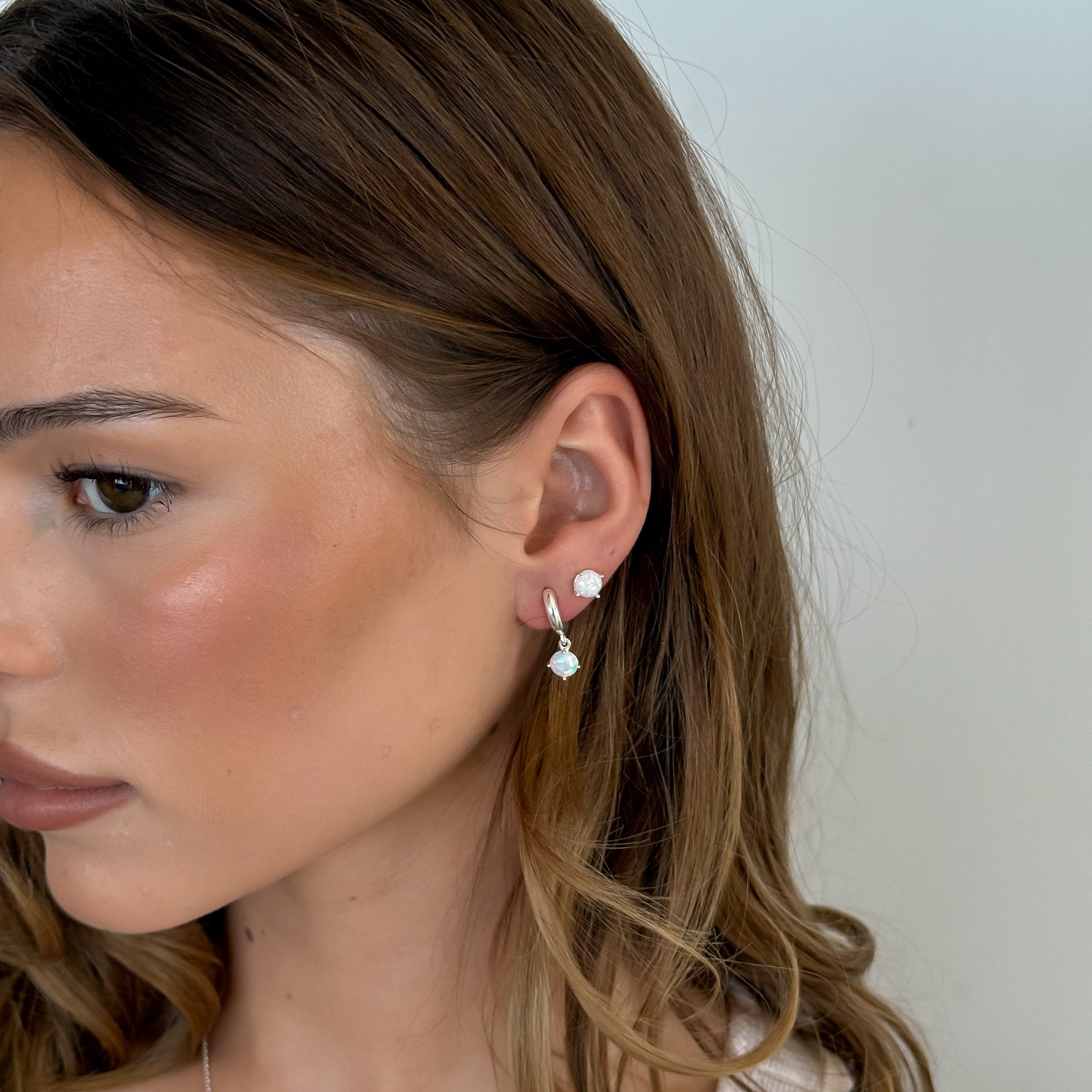 Close-up of a woman wearing a small earring with a plain background
