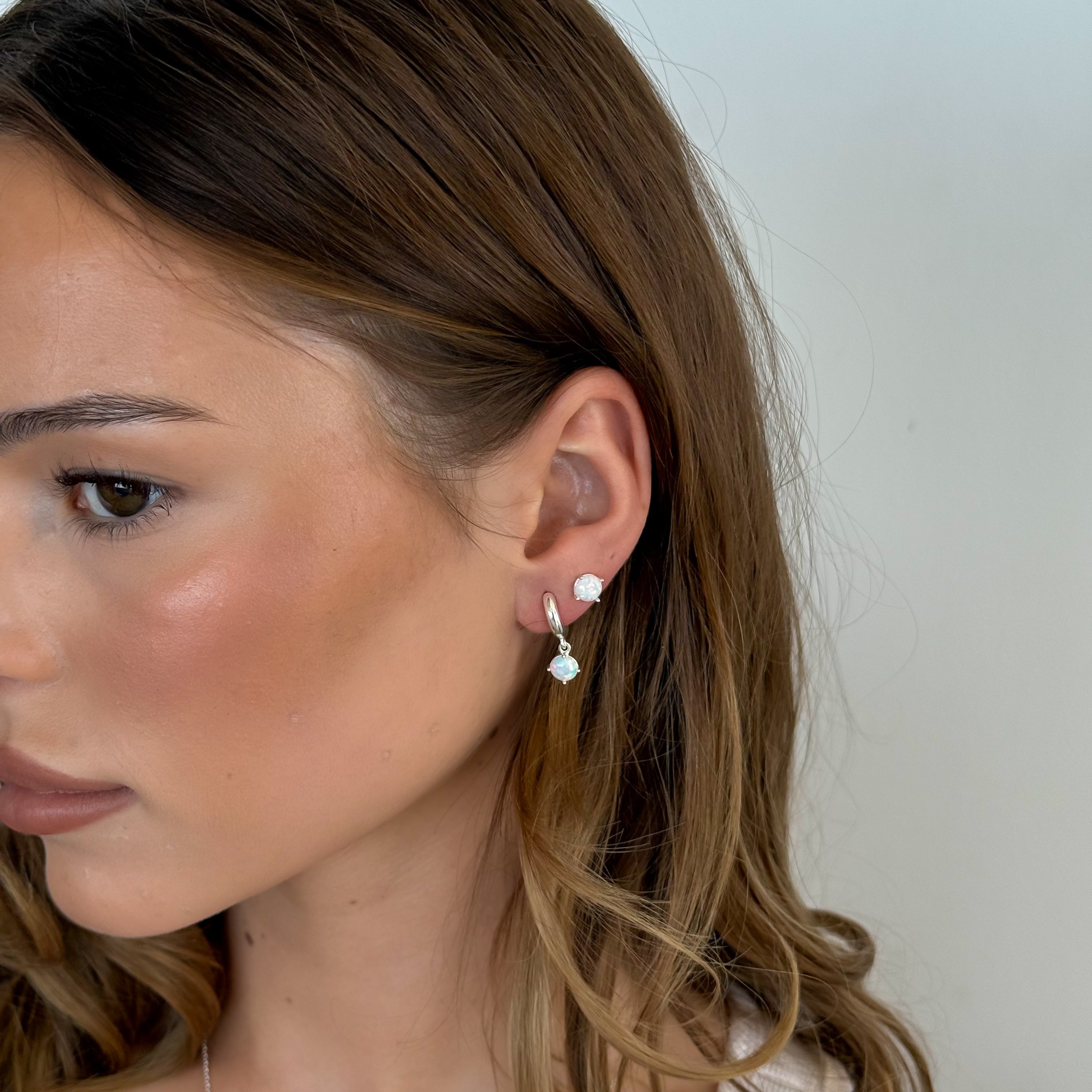 Close-up of a woman wearing a small earring with a plain background