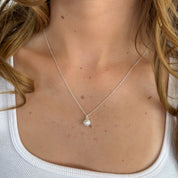 Necklace with a pendant worn by a person, focusing on the necklace.