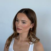 Woman wearing a white tank top against a plain background