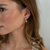 Close-up of a woman wearing a green earring with a plain background