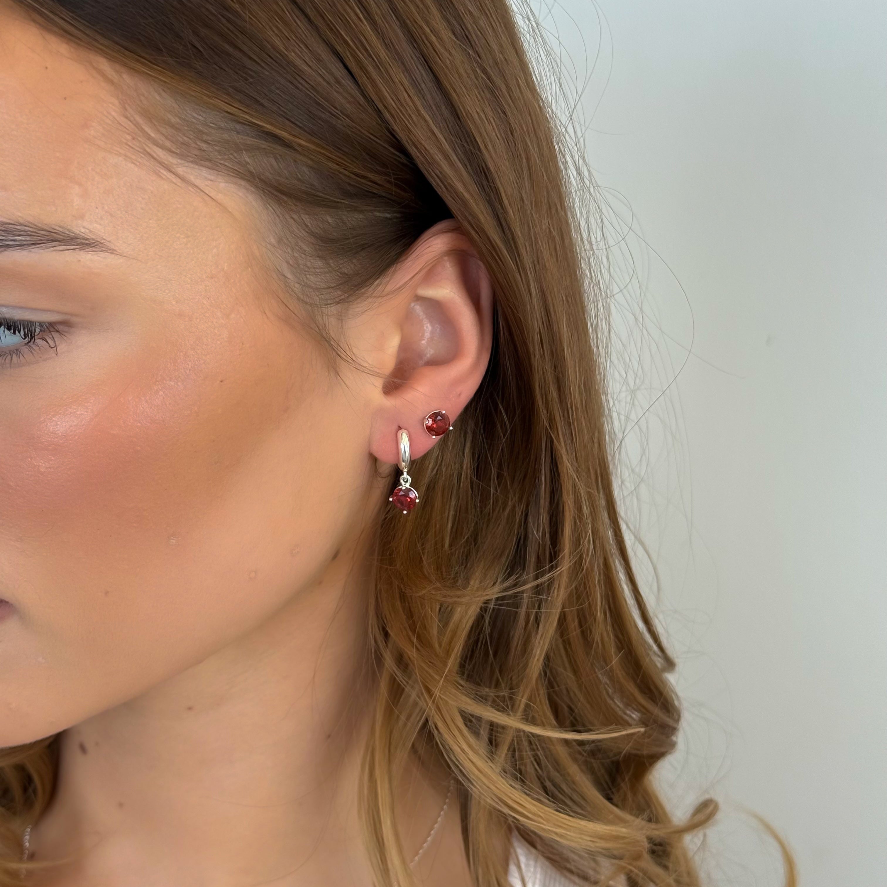 Close-up of a person wearing earrings with a neutral background